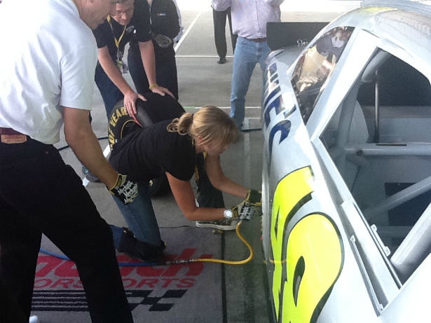 Michelle Beadle changes a tire on NASCAR champion Jimmie Johnson's car as 