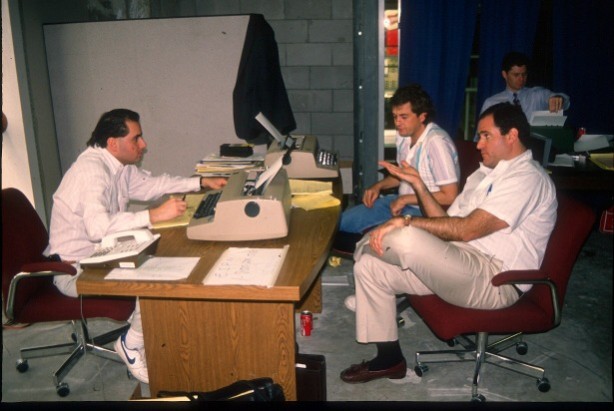 In January 1990,  Chris Berman (right, foreground) huddles with  producers Bob Rauscher (l) and Scott Ackerson in a “production room” on-site meeting in New Orleans for Super Bowl XXIV.  (ESPN)